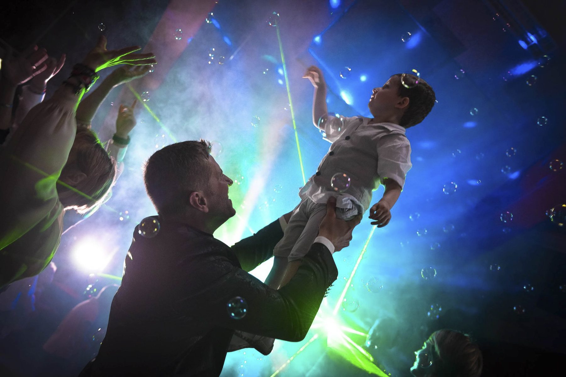 Un père lance son fils en l'air sur la piste de danse d'un mariage, photographié par Kévin Gillon